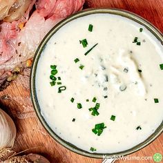 a close up of a bowl of soup on a table next to garlic and meat