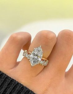 a woman's hand with a diamond ring on top of her finger and an engagement band