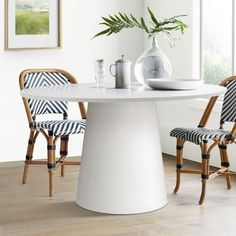 a white table with two chairs and a vase on the table in front of it