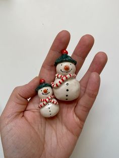 two snowmen are sitting in the palm of someone's hand