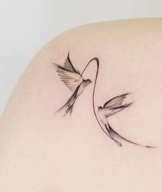 the back of a woman's shoulder with two birds flying around it