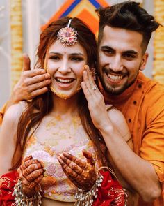 a man and woman posing for the camera with their hands on each other's shoulders