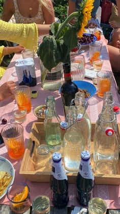 people sitting at a table with drinks and plates of food in front of them on a sunny day