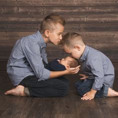 two young boys sitting on the floor with their noses touching each other's heads