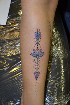 a tattoo on the leg of a woman with an arrow and flower design in it