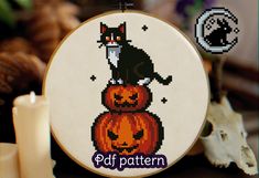 a cross stitch pattern with a black cat sitting on top of a jack o lantern