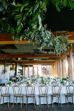 a long table is set up with white linens and greenery for an elegant wedding reception