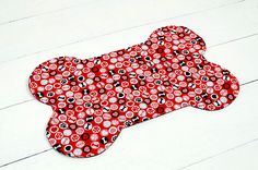 a red and black dog bone shaped rug on a white floor with wood planks in the background