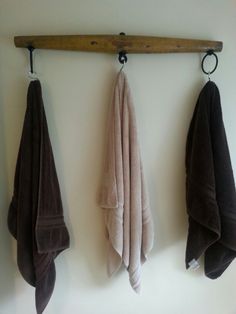 three towels hanging on the wall in front of a towel rack with two wooden hooks