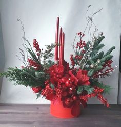 a red candle holder filled with greenery and candles