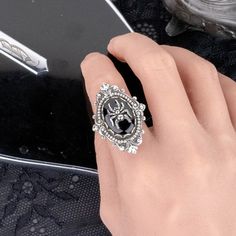 "Add some dark Gothic elegance to your outfit with this black gem and silver spider statement ring. 💀 DESCRIPTION: This novelty ring features a small spider charm that sits on top of a vintage jet black oval cabochon from Swarovski®. This large stone was hand set into a lace edge setting and then layered onto an ornate setting with flourishes and bead detailing. It was mounted onto an adjustable ring base with a simple band. 💀 SIZE: The vintage glass cabochon from Swarovski® measures 3/4 \" long by 1/2\" wide. This is a rare vintage item Article 2190/4. This stone was discontinued and is no longer produced by Swarovski®. The settings were made high quality sterling silver plated brass that was oxidized to give them a vintage feel. They were made and plated in the USA and are lead and nic Spider Ring, Goth Ring, Gothic Elegance, Black Gems, Simple Band, Large Stone, Style Rock, Gothic Rings, Dark Gothic