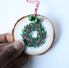 a hand is holding a piece of wood with a christmas wreath on it and candy canes