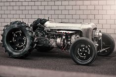 an old fashioned car is parked in front of a brick wall with wheels on it