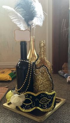 three bottles with feathers in them sitting on a tray next to some other items that are gold and black