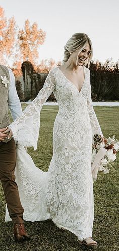 a bride and groom walking through the grass