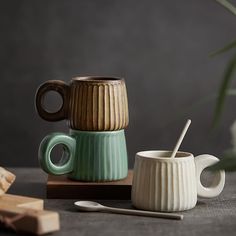 two mugs sitting next to each other on top of a wooden table with a spoon