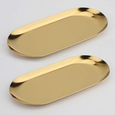 two gold oval shaped trays sitting next to each other