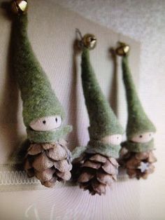 three small pine cones with gnomes on them are hanging from the side of a wall