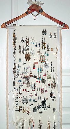 a white wall hanging with lots of earrings on it