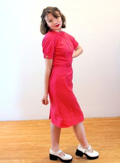 This is a very cute 1950s Bobbie Brooks cotton dress! It's a bright rose-raspberry pink color, in smooth soft cotton with a cute decorative front faux button placket that sports a large white moonglow Lucite button. Two matching buttons open and close at the short sleeve arm openings. The dress is demure with a Peter Pan collar, a trim waist seam with dyed to match string belt loops and a self fabric belt. The dress is shaped with vertical pleats, especially in the upper back where 2.5 inch spac 1950s Pink Vintage Dress With Short Sleeves, 1950s Style Pink Daywear Dresses, 1950s Pink Vintage Summer Dress, 1950s Style Pink Vintage Dress, 1950s Style Pink Dress For Vintage Fashion, Pink 1950s Vintage Dress For Summer, Pink 1950s Vintage Fashion Dress, Pink 1950s Vintage Summer Dress, Pink 1950s Style Vintage Summer Dress