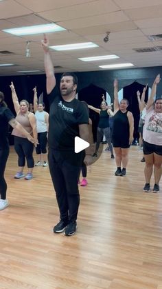 a group of people standing on top of a wooden floor in a dance studio holding hands up