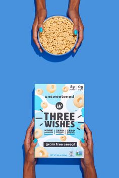 two hands holding a bowl of cereal and a box of three wishes cereal on a blue background