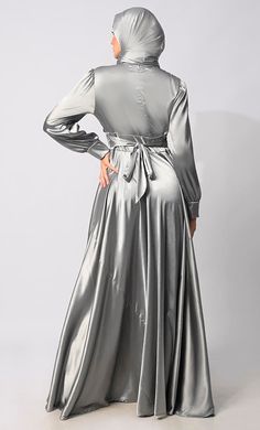 Introducing our exquisite Lycra Satin Flared Abaya, a stunning fusion of elegance and contemporary style. Crafted with meticulous attention to detail, this abaya is designed to elevate your modest fashion wardrobe to new heights. The flared silhouette adds a touch of graceful movement, enhancing the overall allure of the garment. Featuring a front draped pleated style, which adds texture and dimension, creating visual interest and a unique focal point. Complementing the pleats are satin show buttons, delicately embellishing the front of the abaya for a refined finish. For added versatility and cinched-in definition, an attached belt accompanies the abaya, allowing you to adjust the fit according to your preference and accentuate your waistline. The back zipper closure ensures a seamless an Elegant Solid Abaya For Fall, Elegant Solid Color Abaya For Fall, Formal Maxi-length Abaya For Fall, Elegant V-neck Wedding Abaya, Floor-length Fitted Abaya For Party, Fitted Floor-length Party Abaya, Formal Festive Abaya, Party Floor-length Fitted Abaya, Solid Long Sleeve Maxi Dress For Eid