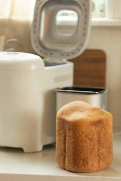 a cake sitting on top of a white counter next to a silver cup and microwave