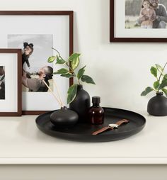 there are two vases with plants in them on the table next to pictures and framed photos