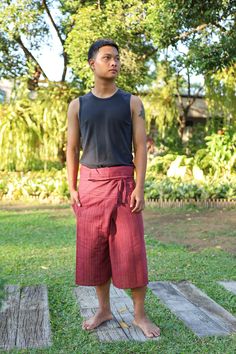 a man standing in the grass with his hands on his hips and wearing red shorts