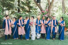 a group of people standing next to each other in front of trees and flowers on the grass