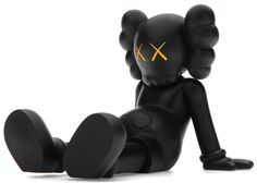 a black toy sitting on the ground with its legs crossed and eyes closed, looking like an x