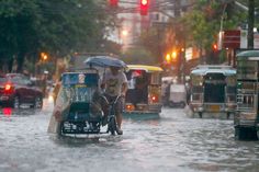 a man riding a bike in the middle of a flooded street with an umbrella over his head