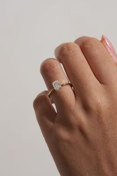 a woman's hand with a diamond ring on top of her finger, against a white background