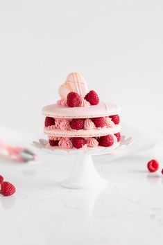 a white cake with raspberries on top