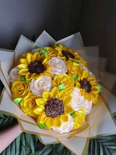 a bouquet of yellow and white flowers sitting on top of green leaves