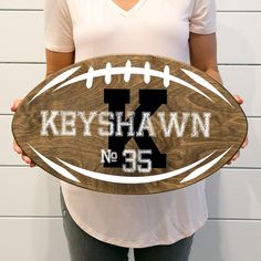 a person holding a wooden sign that says keyshawn no 35 with a football on it