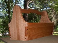 a wooden bed frame sitting on top of a table in front of some trees and grass