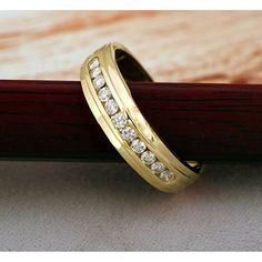 a gold wedding band with diamonds on it sitting on top of a piece of wood