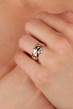 a woman's hand wearing a gold ring with leaves on the middle and sides