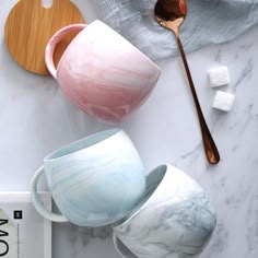 marbled cups and spoons on a white table with wood serving utensils