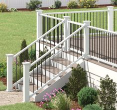 a set of stairs leading up to a white fenced in area with flowers and shrubs