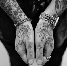 two hands with tattoos on them are holding something in their palms and the other hand is showing