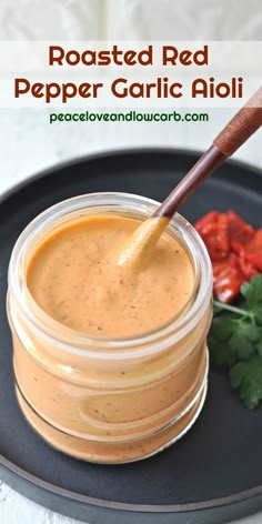 a jar of roasted red pepper garlic aioli on a plate with tomatoes and cilantro