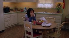 a woman sitting at a kitchen table eating food