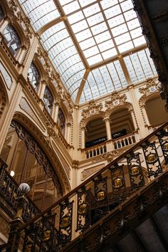 the inside of a building with glass ceiling and wrought iron railings on each floor