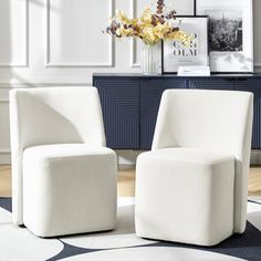 two white chairs sitting next to each other on top of a rug in a living room