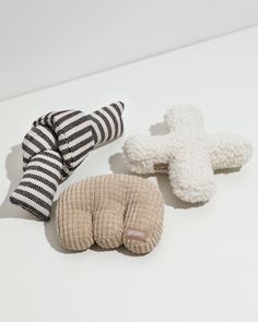 three stuffed animals sitting on top of a white table next to each other with black and white stripes