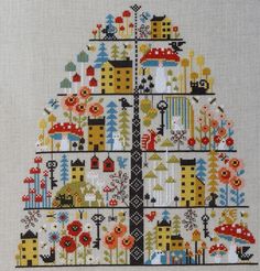 a cross stitch christmas tree with houses and flowers