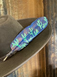 Vibrant Arizona Cacti stand out against the deep blue and copper evening sky. A beautiful a desert scene, and some of the paint is metallic. Looks good on any color hat! Feather Symbolism, Arizona Cactus, Desert Scene, Watercolor Feather, Hat Hanger, Floral Hat, Blue Feather, Evening Sky, Star Spangled